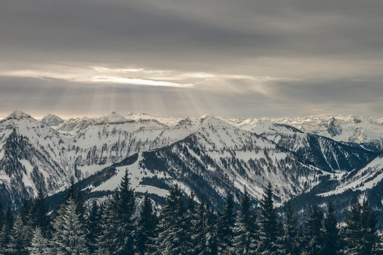 sun beams llluminating snowcovered alpine mountain landscape