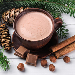 Christmas cup of hot cocoa with milk, broken chocolate cubes, hazelnut and cinnamon sticks,...