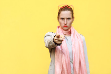 The beautiful woman, wearing autumn coat, having  shocked looks, pointing finger at camera.