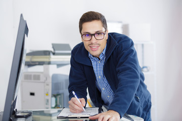 man leaning over open photocopier during maintenance check