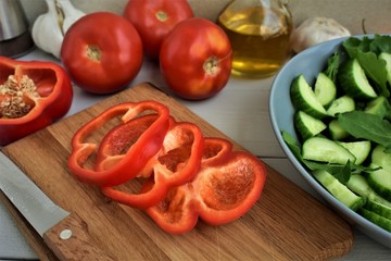 Red paprika sliced on the cutting board, whole tomatoes and olive oil.