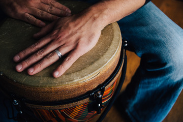 Hands of a man playing a djembe drum