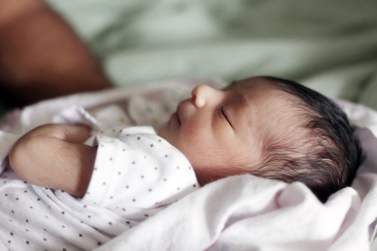 Newborn baby lying  on Bed and Wrapped In a Blanket