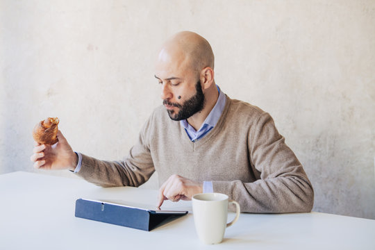 Young man is using the tablet at the breakfast