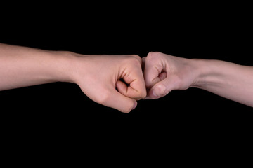 The image close-up of the collision of two fists on a black background. The concept of confrontation, competition or friendship