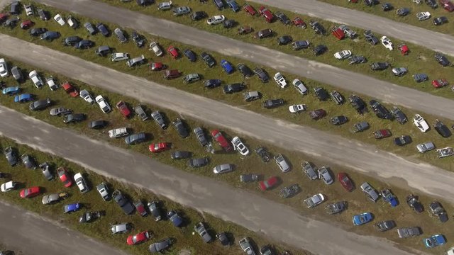aerial automotive scrapyard above rotating view of rows of cars 4k