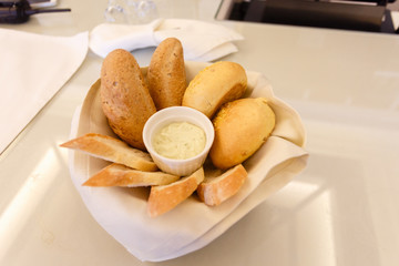 Fresh bread in a white plate with a bowl for the sauce in the center. Selective focus