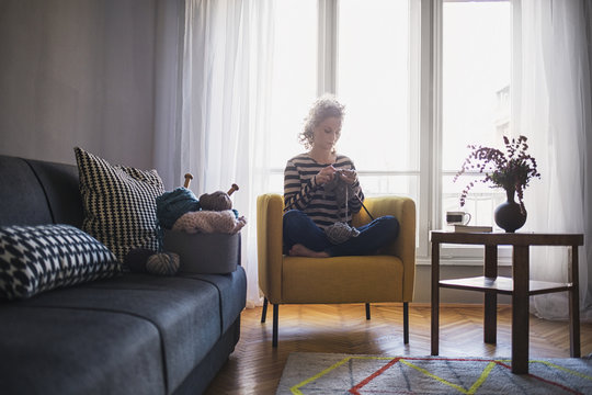 Woman Knitting a Scarf in the Living Room