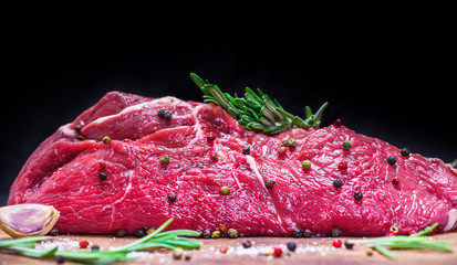 raw beef tenderloin on a board with spices and rosemary