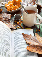 Naklejka na ściany i meble Autumn (fall) cup of tea and colorful leaves over rustic wooden background