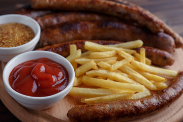 Appetizing beer snacks set close up. Assorted sausages, french fries served with spicy tomato sauce and mustard on the board. Oktoberfest food, pub concept