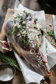 Leg of lamb with garlic and rosemary being prepared for roasting.