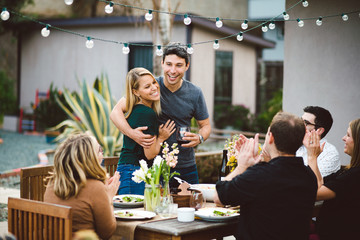 Couple making an announcement at a backyard dinner party.