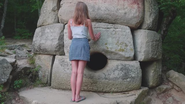 Young caucasian girl standing and touching an ancient dolmen