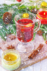 New Year's mulled wine in a glass on the background of twigs, candles and garlands.