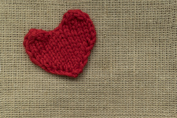 red knitted heart lies on a wooden board