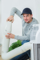 Man working on hose of air conditioning unit