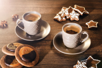 Hot espresso in a cup with New Year gingerbread in the form of a snowflake and a star. Two cups of coffee on a wooden background.