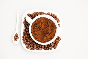 White coffee cup, coffee plate and teaspoon with coffee beans and coffee powder
