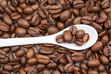 Coffee beans and small, white teaspoon 
