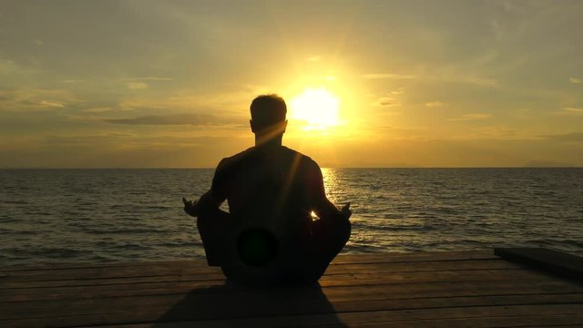 Man meditation alone at sunset. Man's silhouette at the sea.
