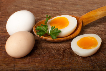 Boiled egg in a wooden spoon on a board