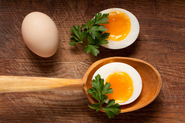 Boiled egg in a wooden spoon on a board