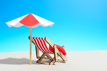 Merry Christmas on beach concept. Lounge chair with umbrella and Santa hat
