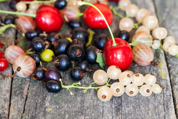 Currants, cherries and other summer fruits with old wood texture
