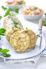 Deftiger bayerischer Serviettenknödel in Scheiben geschnitten, Sauerkraut mit Speck im Hintergrund...
