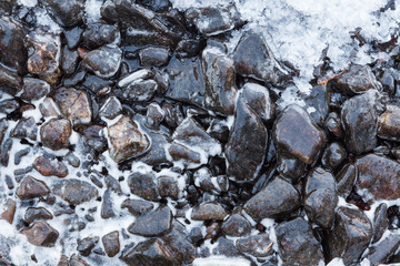 Small rocks covered in ice at lake shore