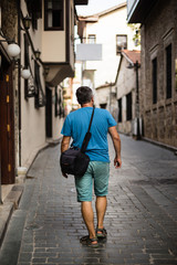 Fototapeta na wymiar Traveller with camera bag walking through the narrow streets of 