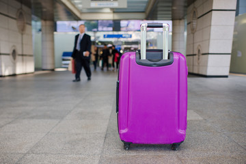 Suitcase on wheels standing on the floor in modern airport terminal. Copy space