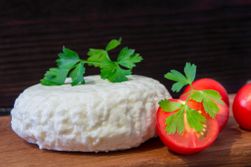 Young oak cheese cutting Board with tomatoes and parsley. Mozarella for pizzas and salads.