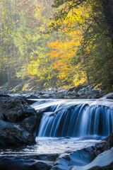Fototapeta na wymiar Smooth flowing water falling over rocks downstream in forested environment landscape scene