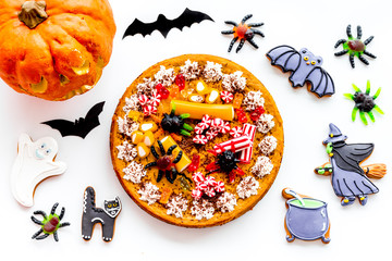 Halloween bakery and sweets. Pumpkin pie, gummy spiders, gingerbread cookies on white background...