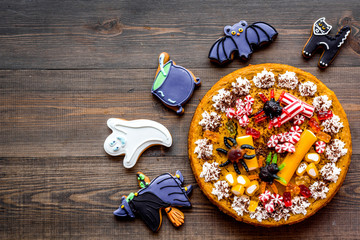 Halloween bakery and sweets. Pumpkin pie, gummy spiders, gingerbread cookies on wooden background top view copyspace