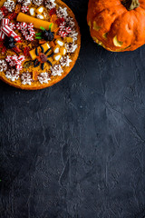 Halloween tradition. Pumpkin pie and pumpkin with scary face on black background top view copyspace
