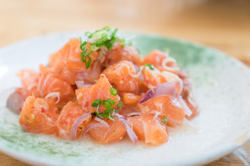 Japan salmon spicy salad with herbs. Mix Japanese and Thai food between Japan salmon sashimi and Thai herb in Japanese restaurant..