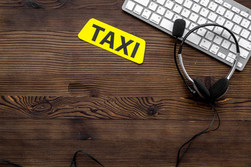 taxi call-center operator equipment with keyboard and headphones on wooden background top view...