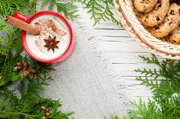 eggnog cocktail in mug arranged with christmas decoration and cookies box on white wooden table