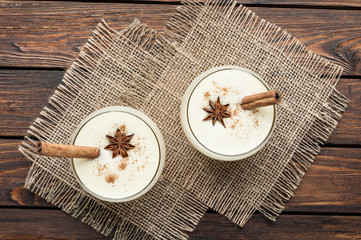 eggnog cocktail in glasses arranged with christmas decoration on wooden table