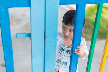 Sad Asian kid behind the grid trying to escape. shallow DOF