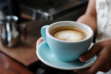 Woman hands holding green coffee cup at cafe background, close up, food and drinks concept