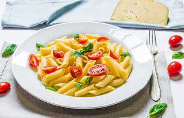 Colorful penne rigate pasta dish with cherry tomatoes and basil leaves