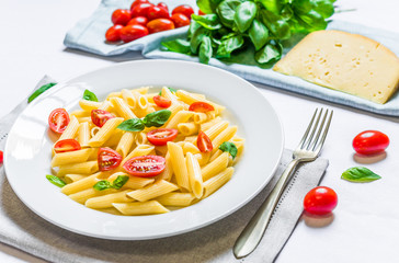 Colorful penne rigate pasta dish with cherry tomatoes and basil leaves