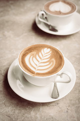White cup with latte coffee and cake