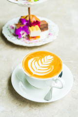 White cup with latte coffee and cake
