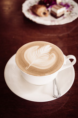 White cup with latte coffee and cake