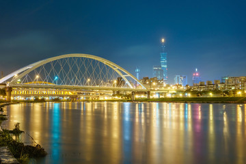 Night scenery of Taipei City with beautiful reflections of skyscrapers & bridges on the water by riverside at dusk. Cityscape of Taipei 101 Tower, Keelung River, Xinyi District & downtown in twilight
